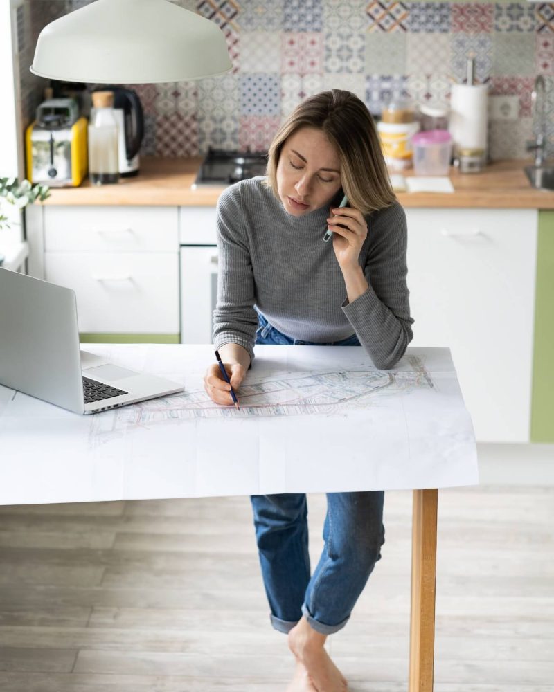 woman-talking-on-cellphone-discusses-the-details-of-an-architectural-project-makes-notes-on-drawing-1.jpg